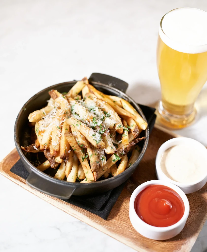 French fries with cheese and herbs, beer, and two dipping sauces.