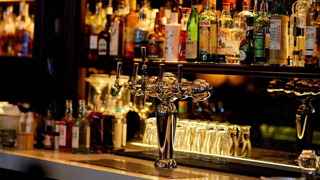 Well-stocked bar counter with beer taps, liquor bottles, and empty glasses.
