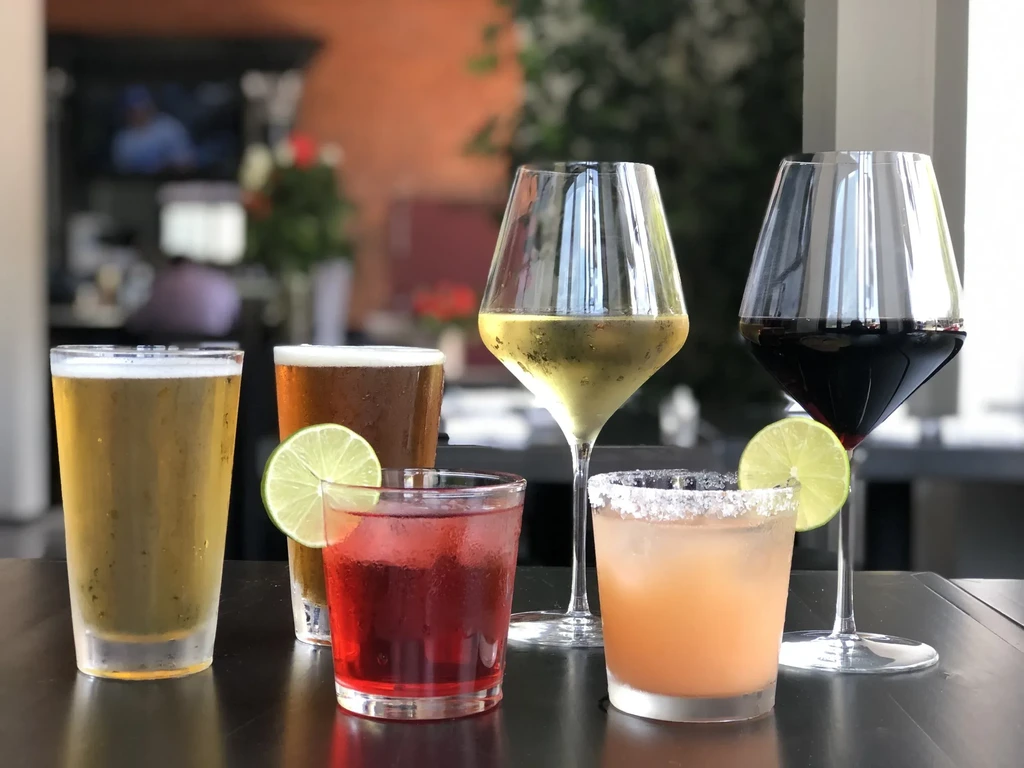 Six cold beers, wines, and cocktails on a dark table.