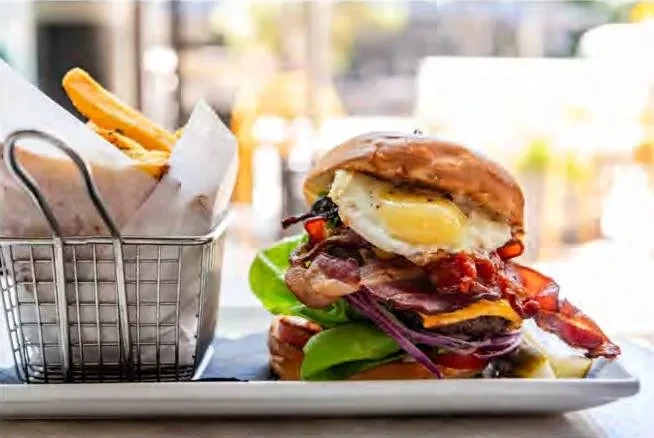 Gourmet burger with fried egg and bacon, alongside golden french fries.