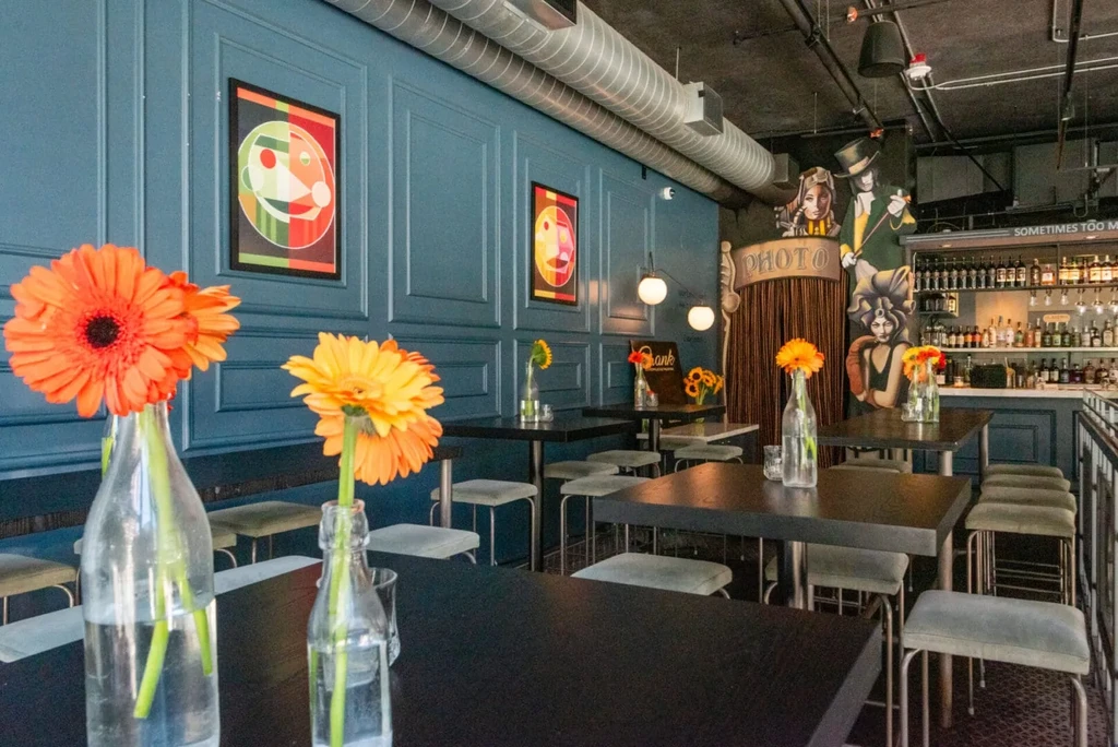 Restaurant interior with bar, vintage photo booth, and colorful wall art.