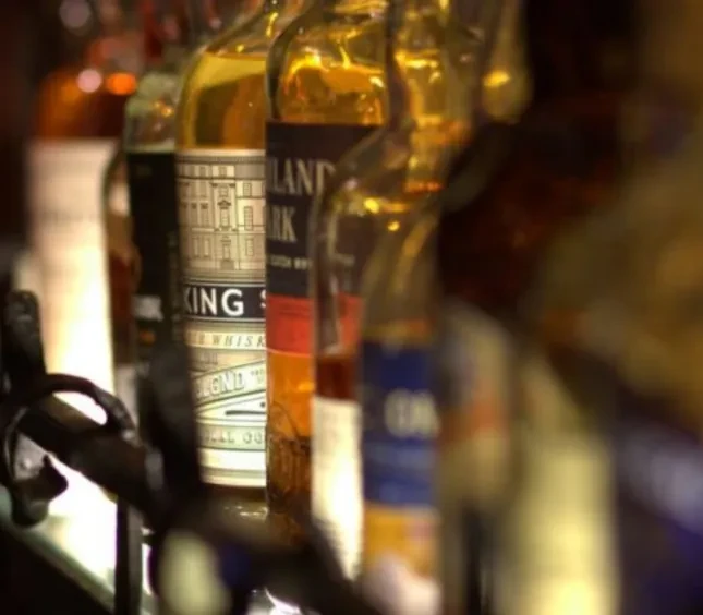 Amber liquor bottles in shallow focus, "KING S" and "HIGHLAND PARK" visible.