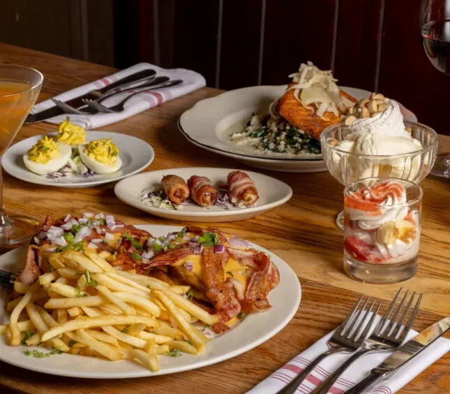 Vibrant tabletop scene with diverse restaurant dishes, desserts, and drinks.