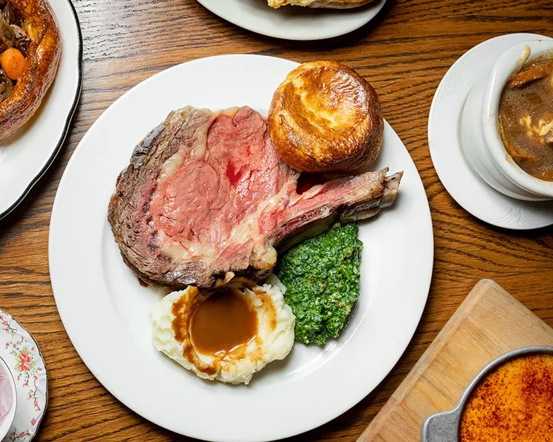 Overhead view of prime rib with Yorkshire pudding, mashed potatoes, and green vegetables.
