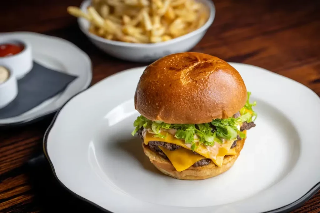 Close-up photo of a double cheeseburger, fries, and two dipping sauces.