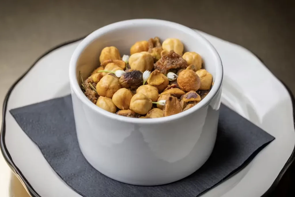 Small ceramic bowl filled with nuts, dried fruit, and white flowers.