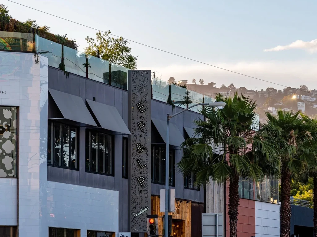 Modern building exterior with E.P. & L.P. sign, palm trees, and rooftop greenery.