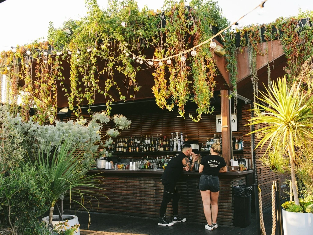 E.P. & L.P. Restaurant rooftop bar with patrons and lush greenery.