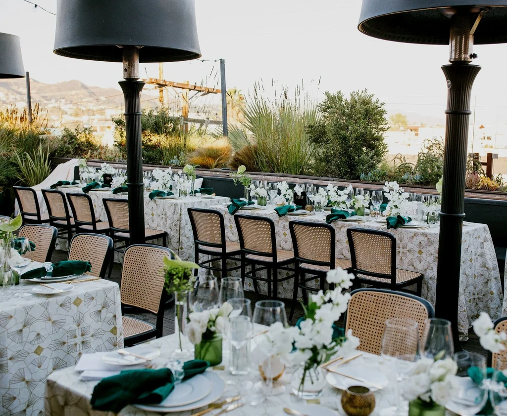 Elegantly set outdoor tables, patio heaters, lush greenery, mountain view.