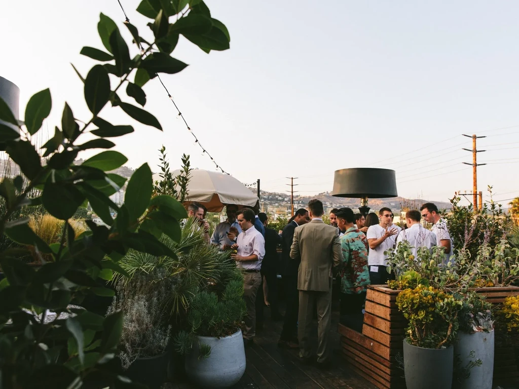 Bustling group enjoys drinks on a sophisticated outdoor patio at dusk.