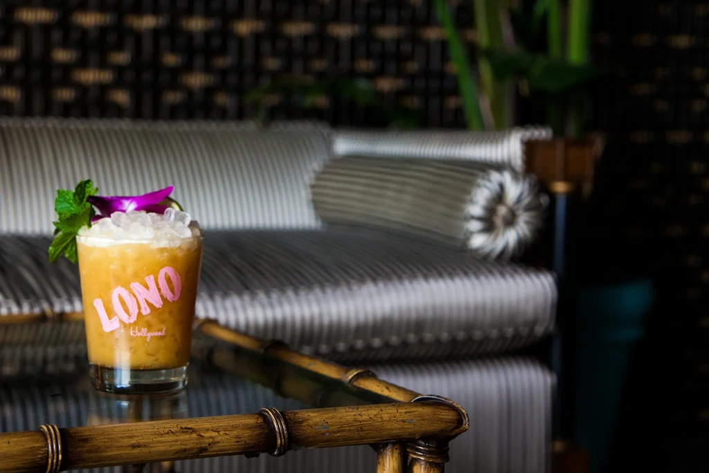 Light orange LONO cocktail with crushed ice, mint, and purple orchid.