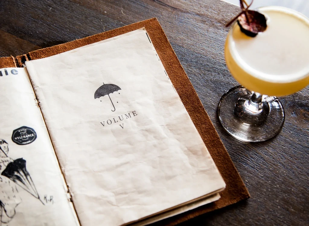 Open rustic menu with umbrella graphic and a yellow cocktail.