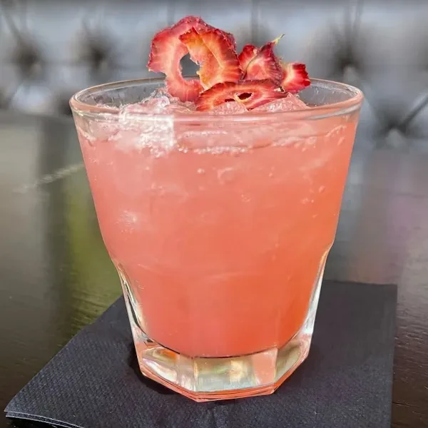 Faceted glass, pink drink, crushed ice, dried strawberry slices.