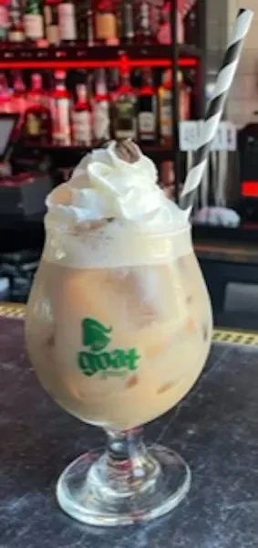 Iced coffee in stemmed glass, whipped cream, coffee bean, striped straw.