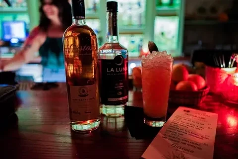 Giróso rum, La Luna mezcal, and red cocktail on a wooden bar.