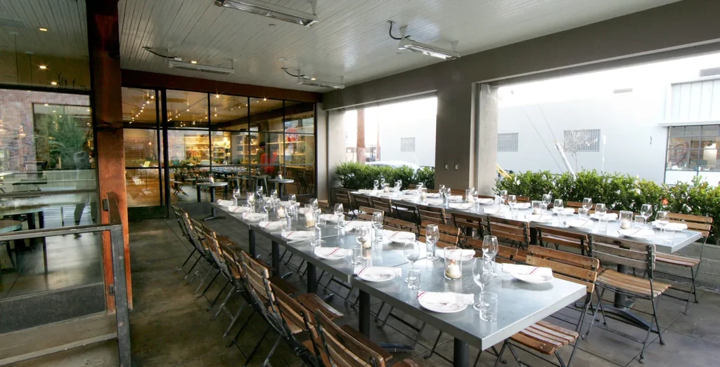 Modern restaurant patio with long tables set for dining.