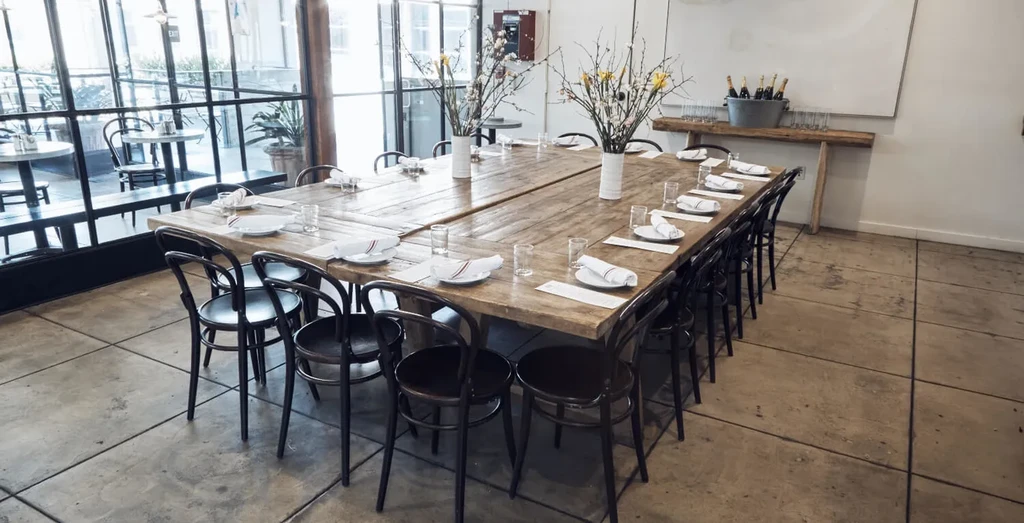 Empty private dining room with rustic table, floral centerpieces, champagne.