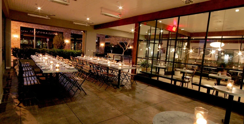Warmly lit restaurant patio and indoor dining area at night.