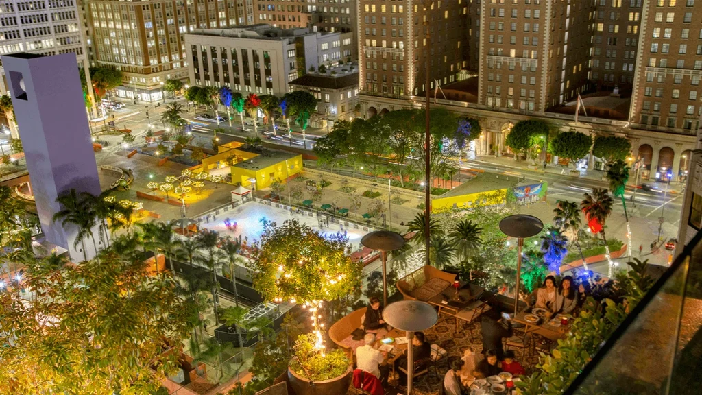 Night aerial: bustling rooftop, vibrant ice rink, and illuminated city.