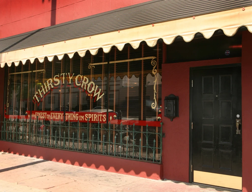 The Thirsty Crow: red building with a door and ornate window.