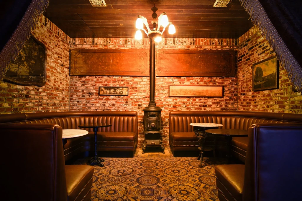 Cozy rustic restaurant with brick walls, leather booths, and a central stove.