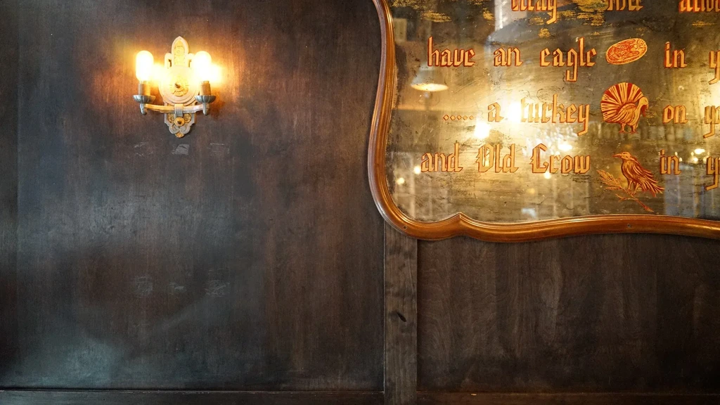 Ornate sconce, distressed wood wall, and antique etched mirror.