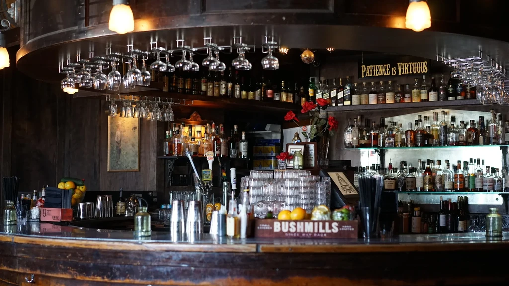 Detailed view of a classic bar with liquor bottles, tools, and warm lighting.