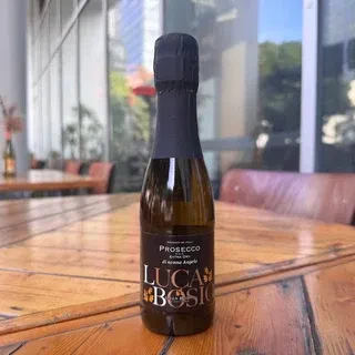Luca Bosio Prosecco bottle with black label on rustic wooden table.