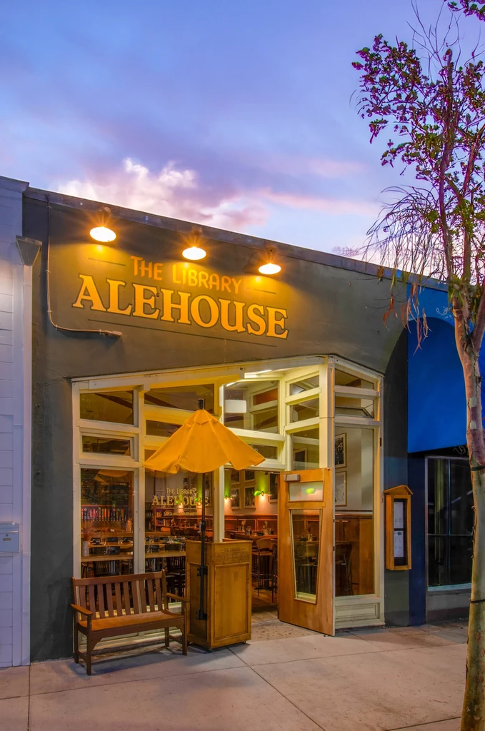 Library Alehouse exterior at twilight, illuminated sign and colorful sky.