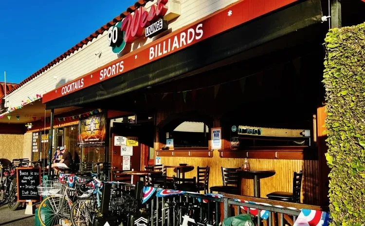 Exterior of 90 West Lounge, red awning, bicycles, and patriotic buntings.