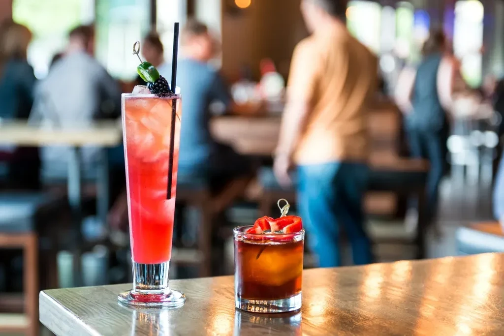 Two cocktails, one red-orange with pepper, one amber with strawberries.