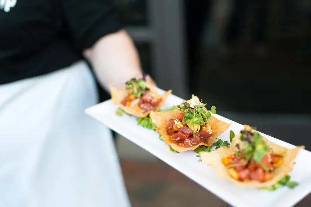 Three wonton cups with diced fish, avocado, and microgreens.