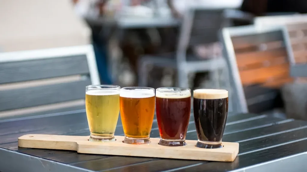 Four cold beers on a paddle, ranging from light to dark.