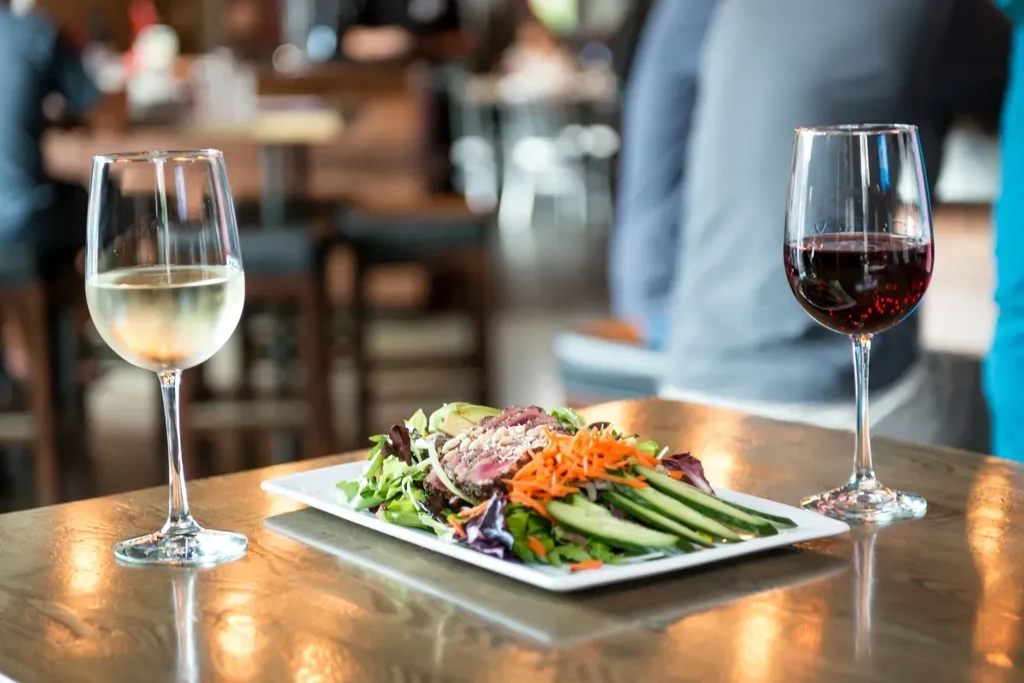 Seared tuna salad, white and red wine glasses on a restaurant table.
