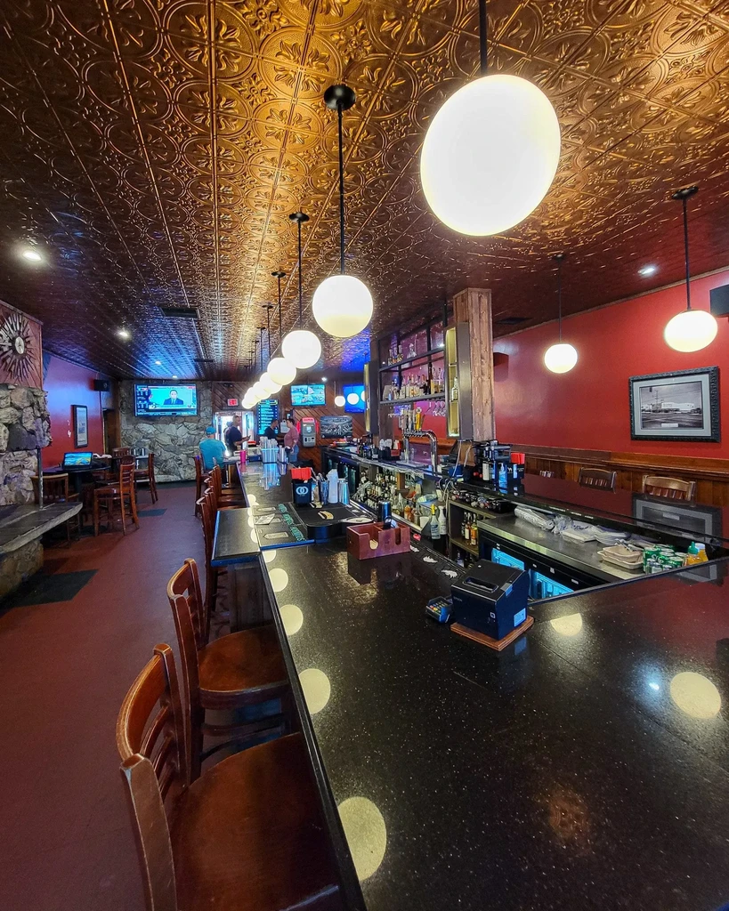 Classic bar interior with long counter, red walls, and copper ceiling.