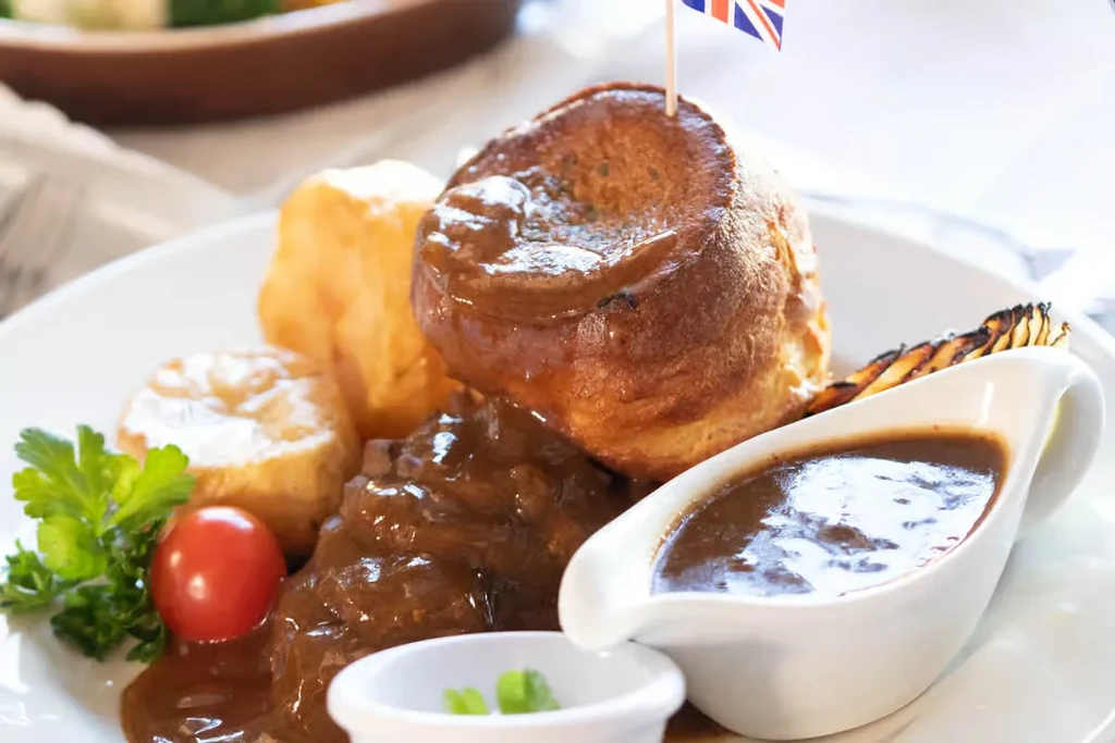 British roast dinner with gravy-covered Yorkshire pudding and flag.