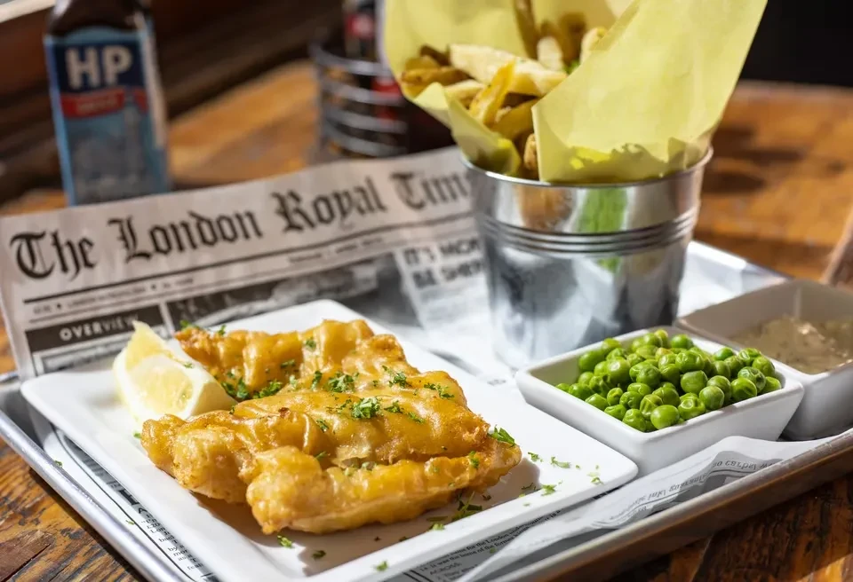 Traditional fish and chips with peas, fries, and tartar sauce.