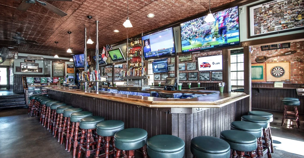 Spacious pub bar with taps, liquor, multiple TVs, and copper ceiling.