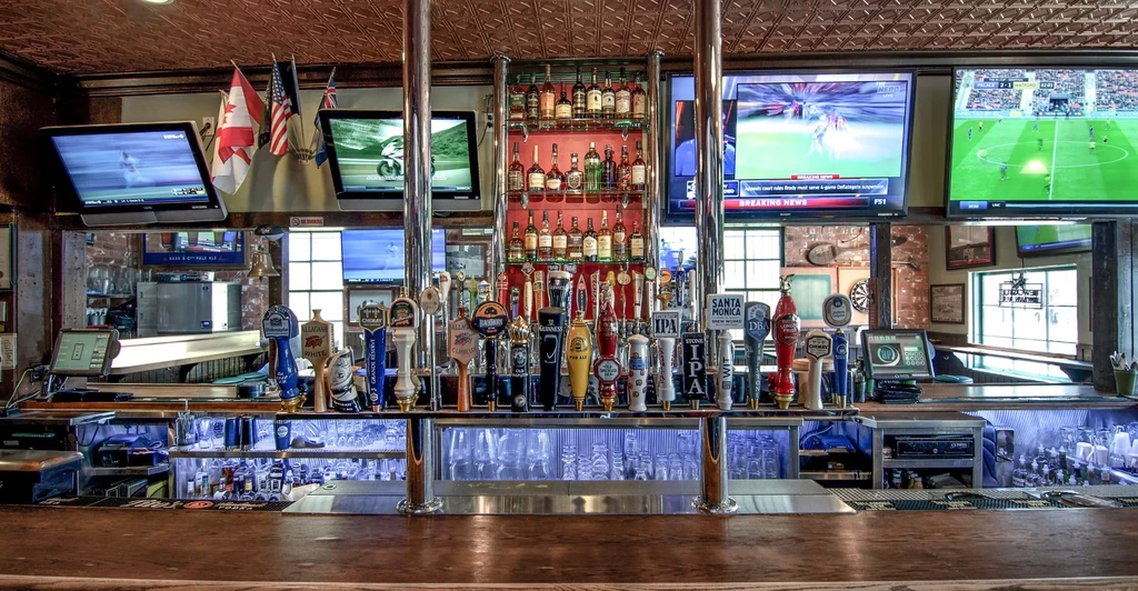 Fully stocked, well-lit sports bar with beer taps and multiple TVs.