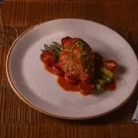 Main course: Sauced protein, asparagus, and tomatoes on a rustic plate.