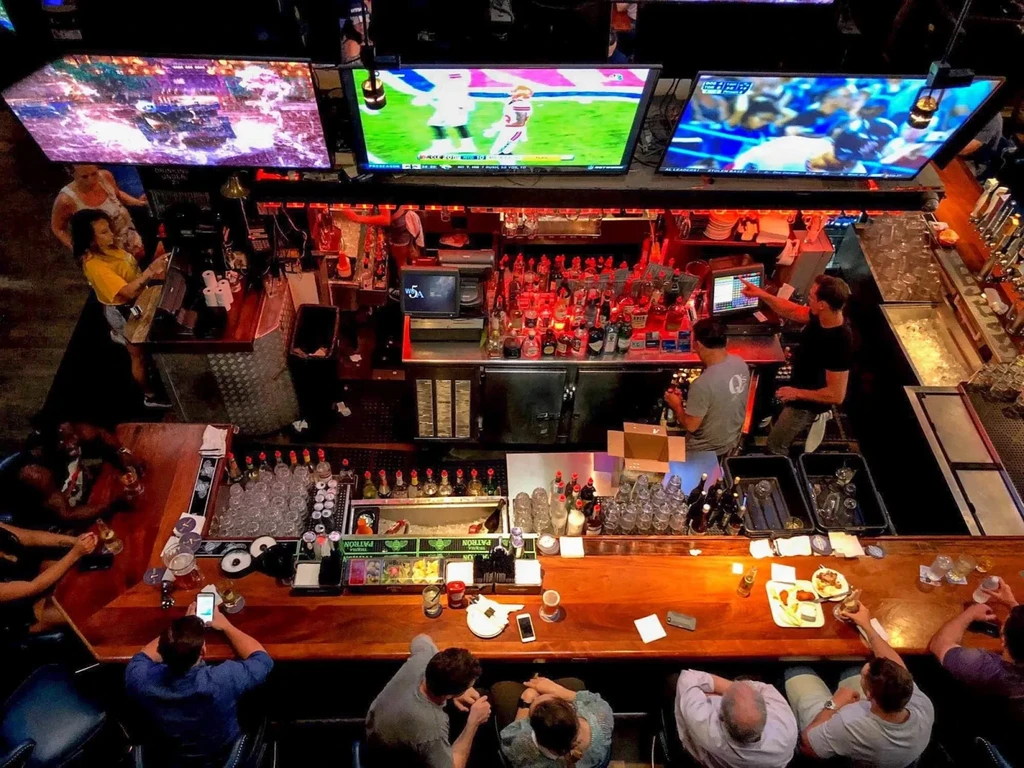 Overhead view of a bustling sports bar with patrons and multiple TVs.