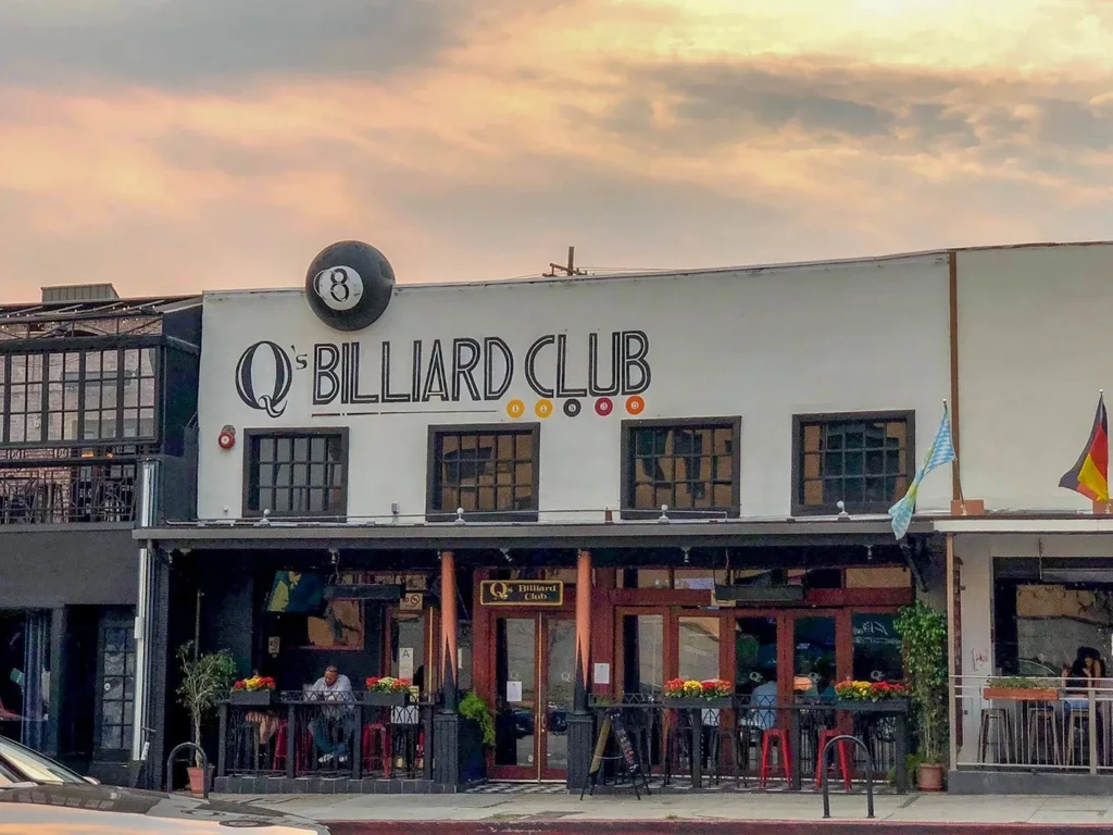 Q's Billiard Club exterior, 8-ball logo, patio, and orange sky.