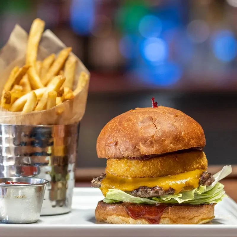 A stacked burger with fries and ketchup on a white plate.