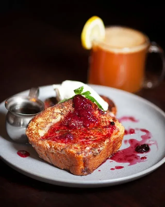 Golden French toast, berry compote, cream, mint, and syrup pitcher.