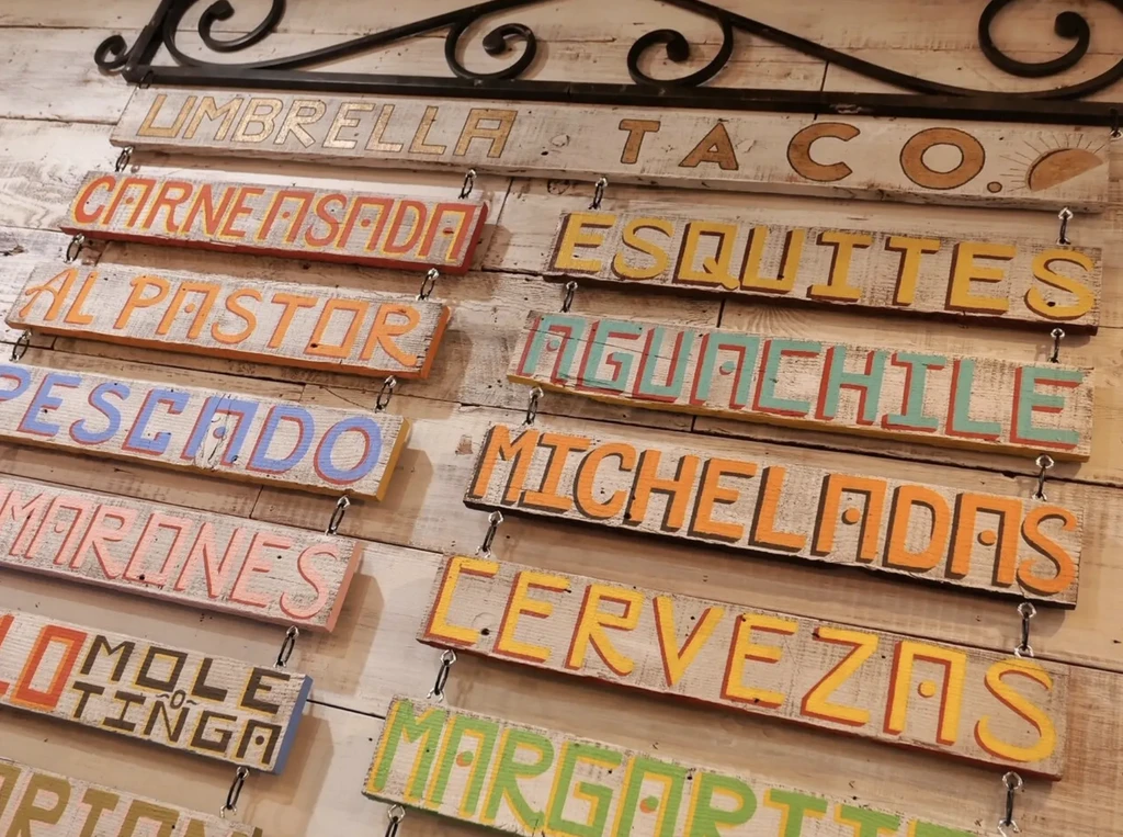 Hanging distressed wooden planks with colorful painted menu items.