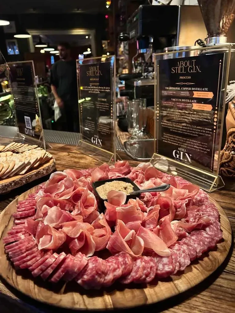 Large charcuterie board with meats and crackers in a cozy bar.