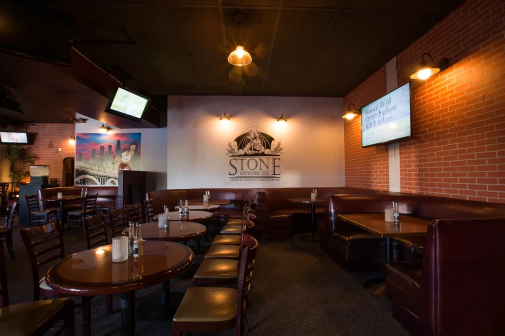 Empty Stone Brewing restaurant interior with booths, tables, and brick walls.