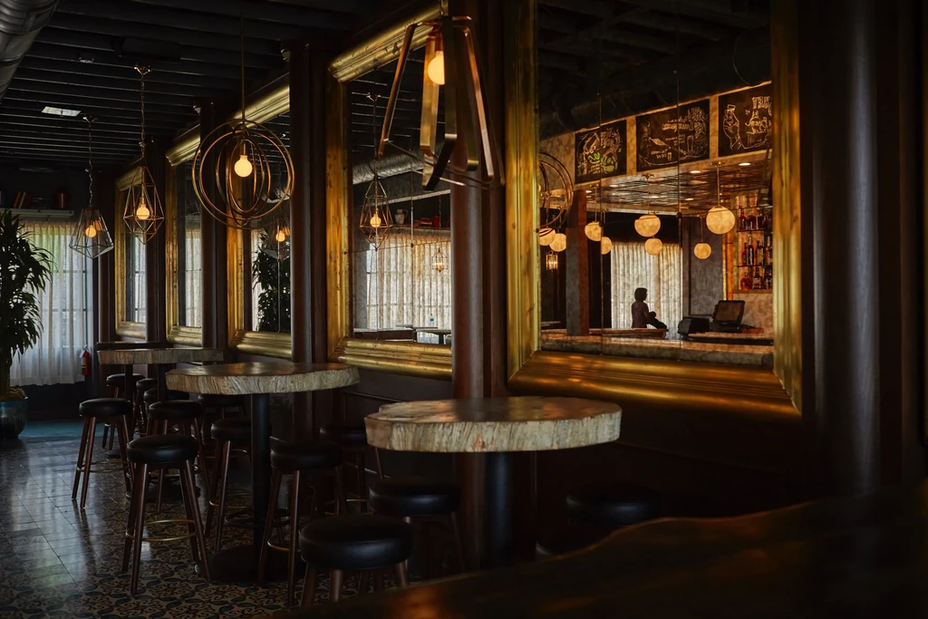 Stylish bar interior with high-top tables, patterned tiles, and pendant lights.