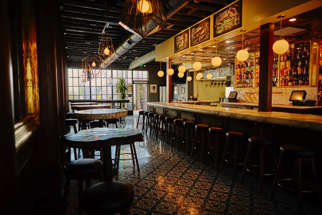 Stylish industrial-rustic bar interior with a long counter and dining area.
