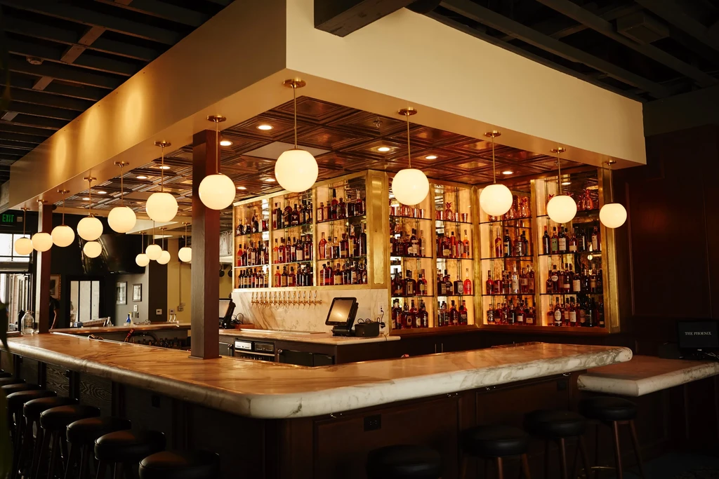 U-shaped bar with marble counter, dark stools, and backlit liquor display.